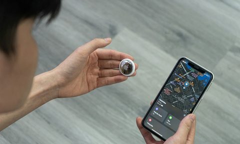 person holding airtag and smartphone