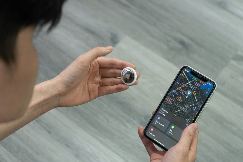 person holding airtag and smartphone