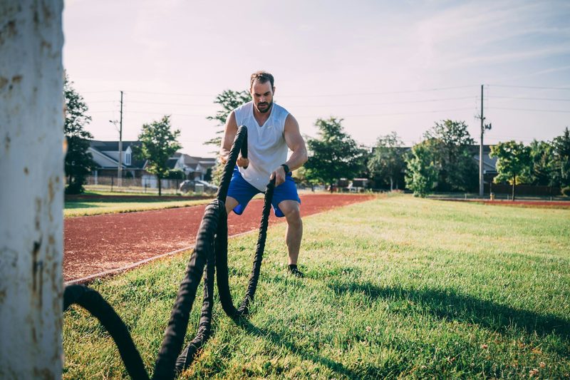 man doing HIIT high intensity interval training outside on grass rope