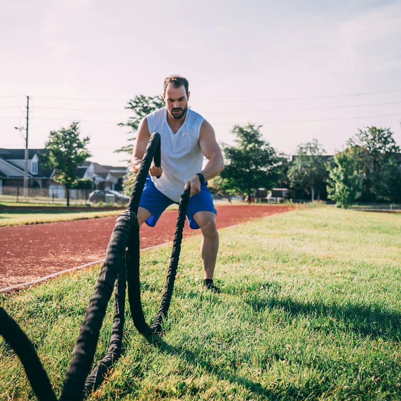 Man doing HIIT high intensity interval training outside on grass rope