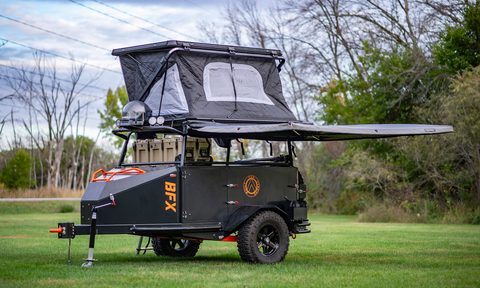 A BFX compact trailer expanded and parked in a grassy field.