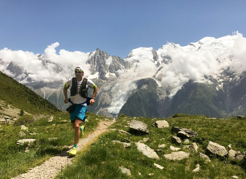 man running on trail mountains in background