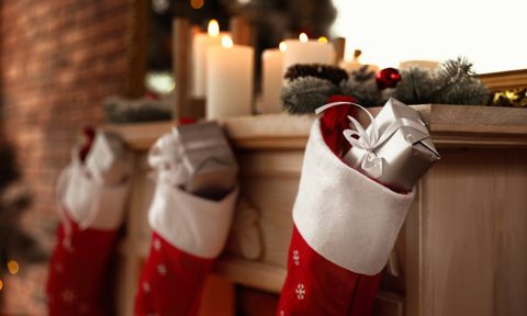 Decorative fireplace with Christmas stocking and gifts in stylish room interior