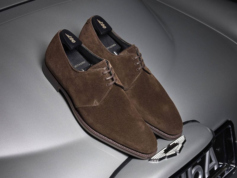 brown suede derby shoes on top of aston martin