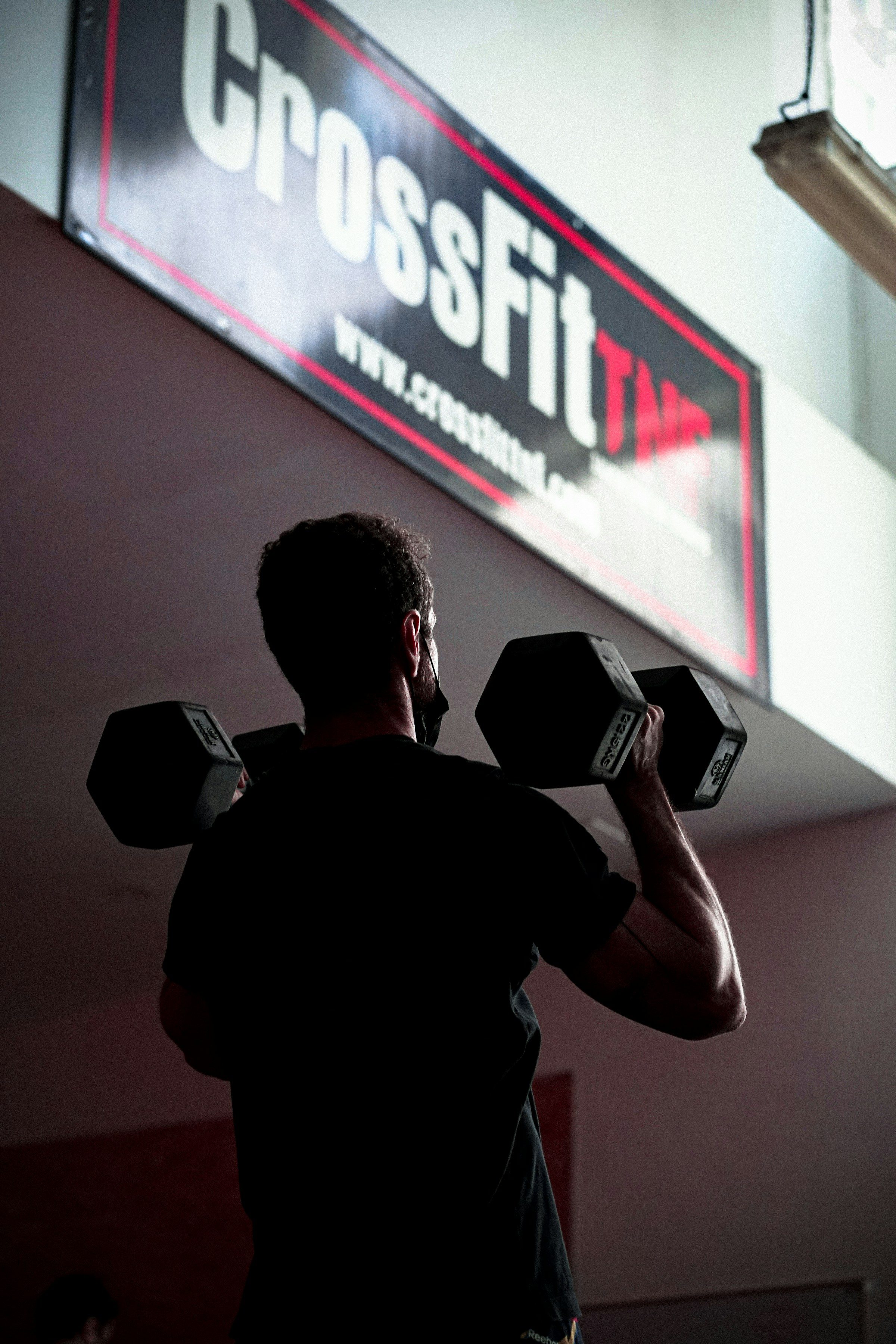 man doing dumbbell shoulder push press in gym crossfit