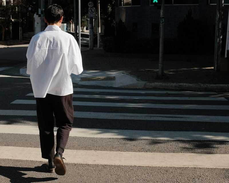 man walking around the block across the street crosswalk