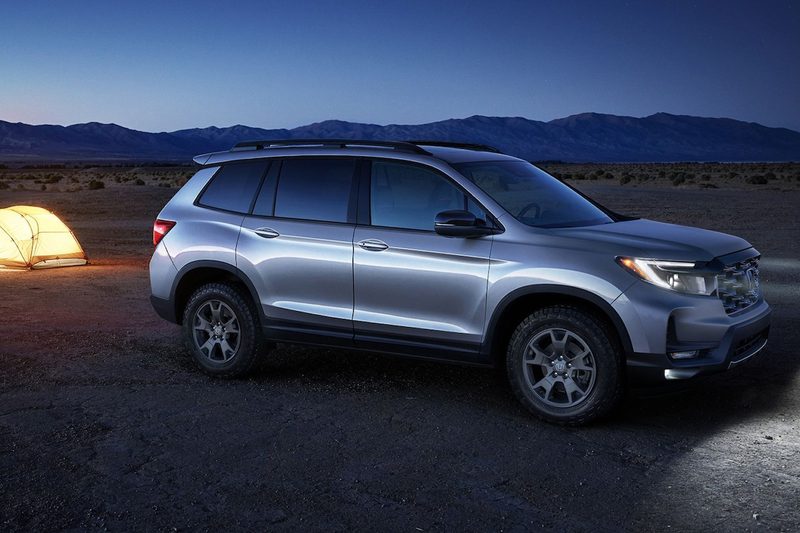2025 Honda Passport TrailSport SUV in the backcountry at dusk with a tent pitched nearby.