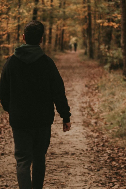 man walking outside in nature hiking trees forest