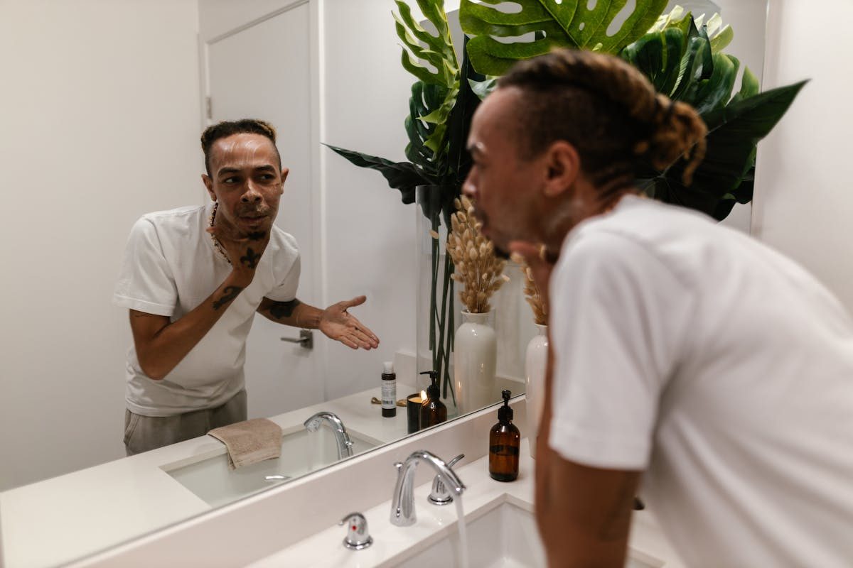young man looking in mirror at skin