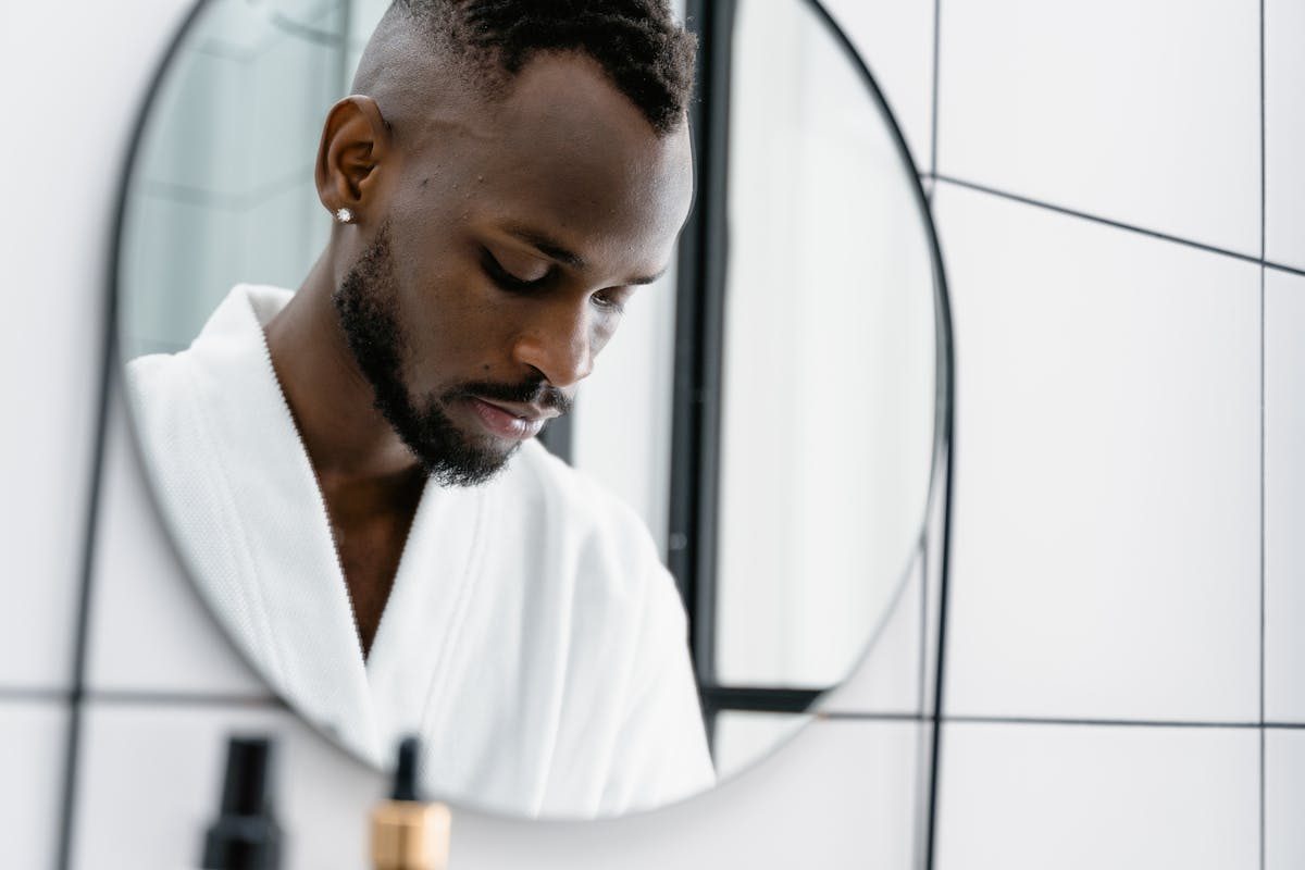 a man looking in the mirror in a white bathrobe