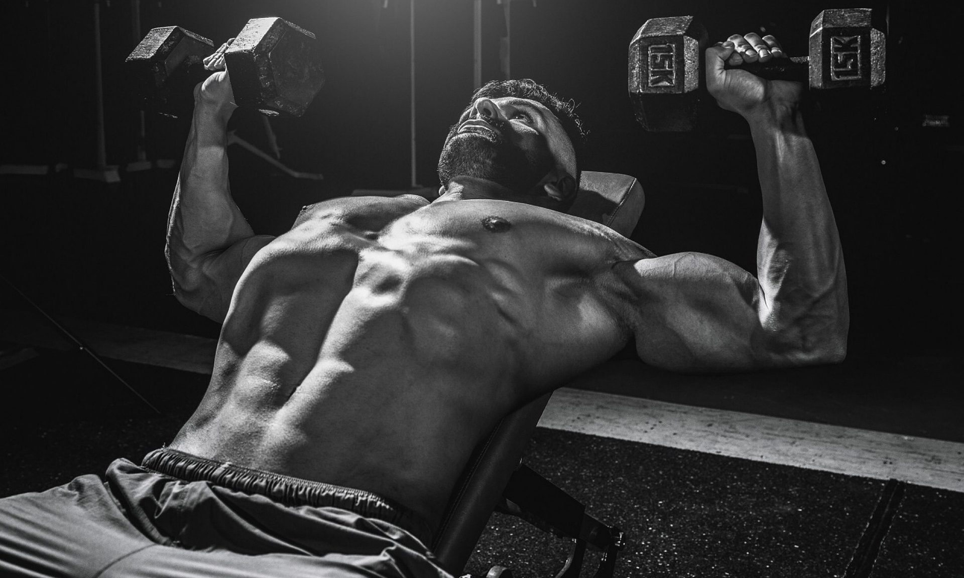 shirtless man lifting weights dumbbells