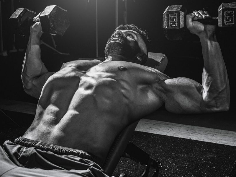 shirtless man lifting weights dumbbells