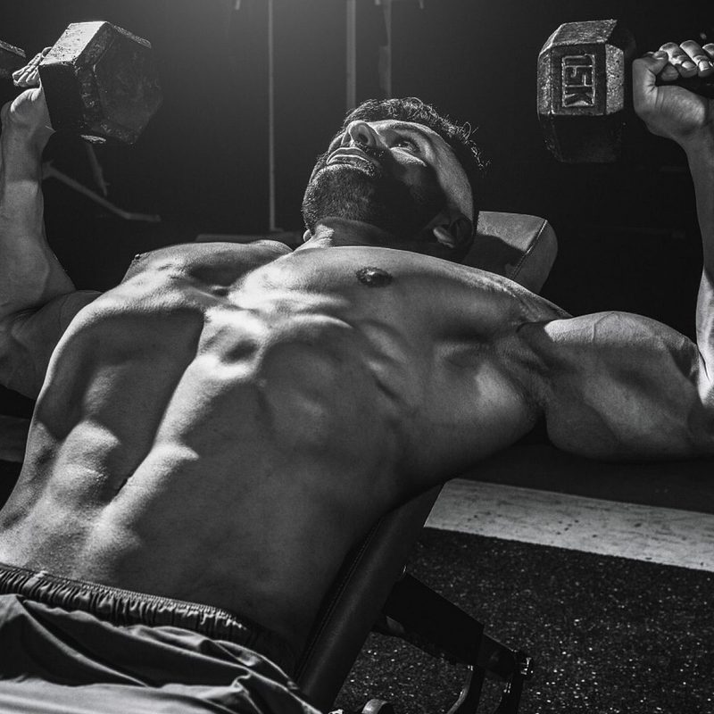 shirtless man lifting weights dumbbells