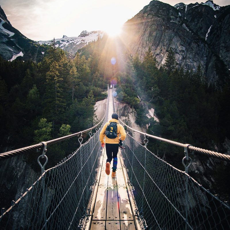 Man walking across a bridge during the day