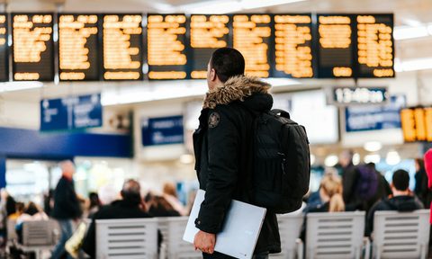 Man standing in airport looking at flight schedule