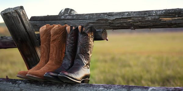 cowboy boots sitting on wood fence