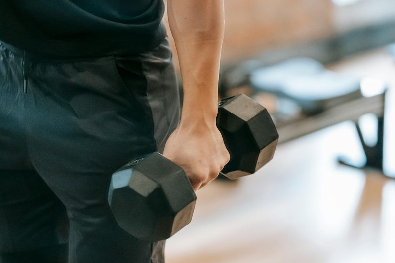 man holding dumbbell arms down by side close up dumbbell shrug