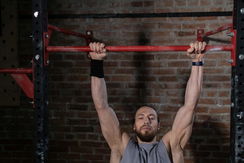 man hanging from pull up bar dead hang pull up exercise strong arms