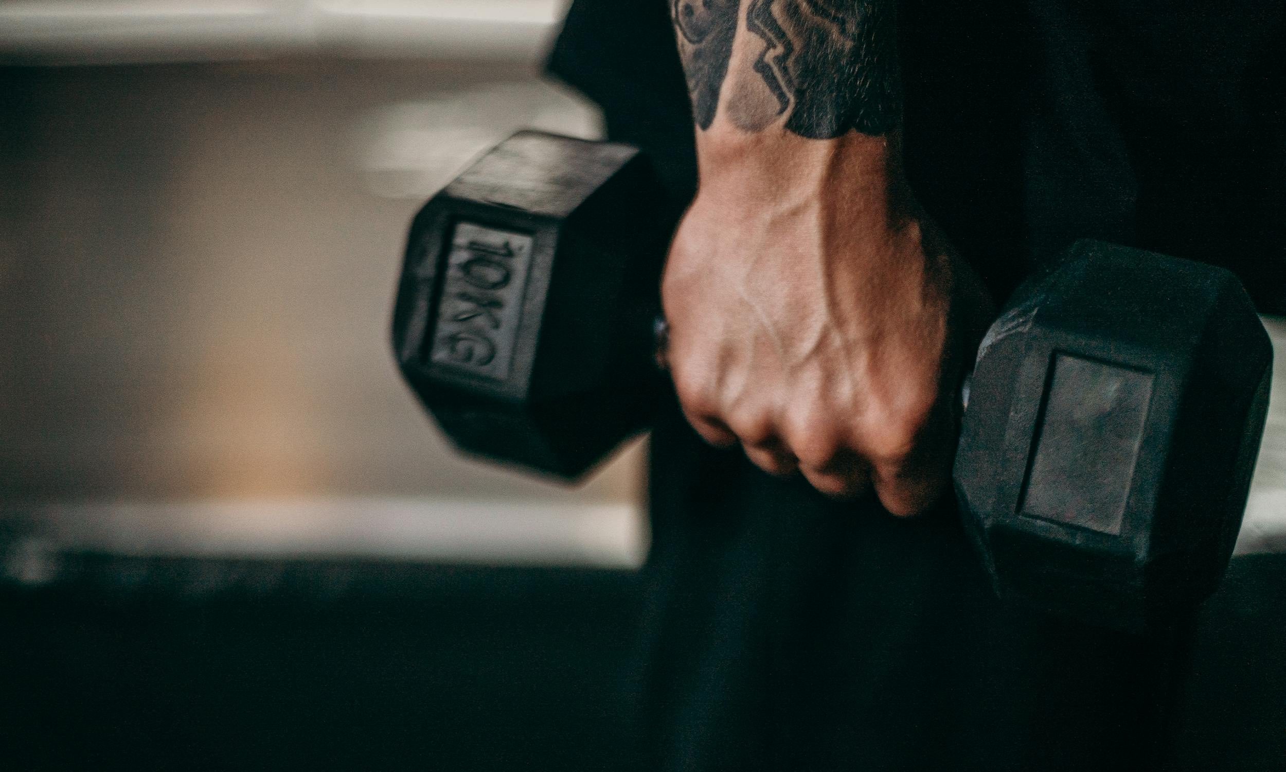 man holding dumbbell in hand dumbbell shrug close up pic tattoo