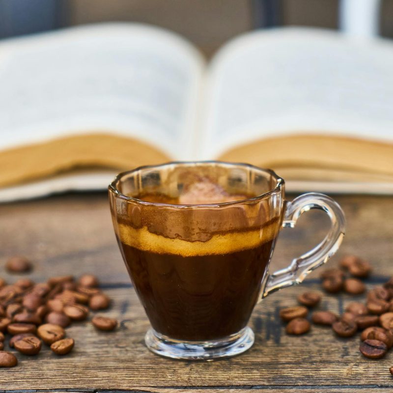 Espresso cup with a book and coffee beans