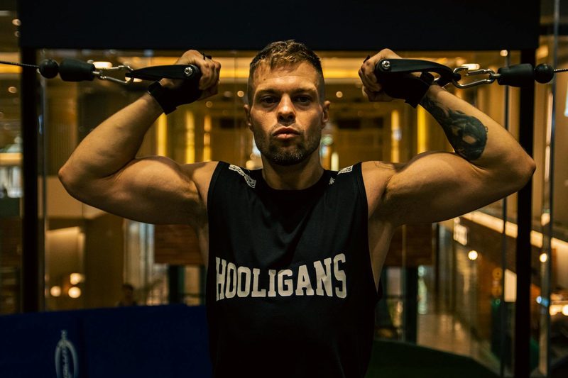 Man doing high cable bicep curl in gym with cable machine