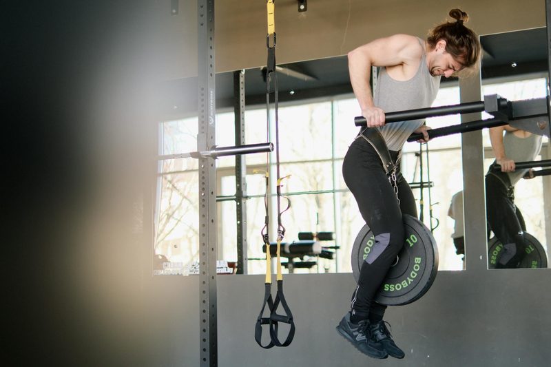 man doing tricep dip on parallel bars dip bars weighted dip in gym