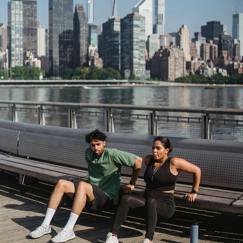 Man and woman outside doing bench dip by water