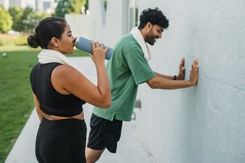 man and woman working out taking break drinking sports drink exercise stretch