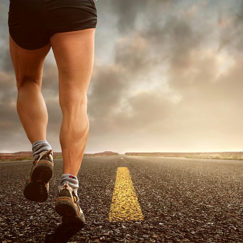Close-up of calf muscles on running legs on road