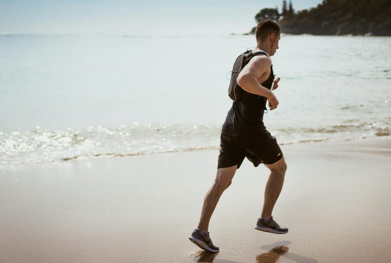 man running with headphones on beach.