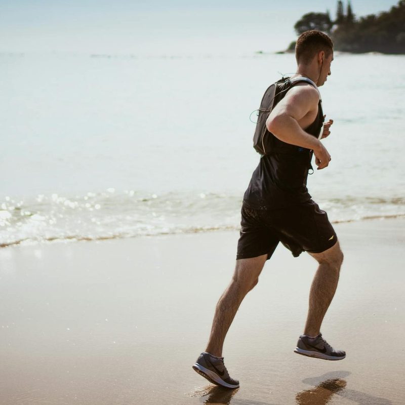 man running with headphones on beach.