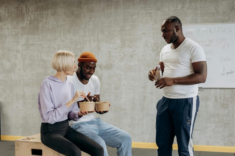 men in gym eating food together bowl