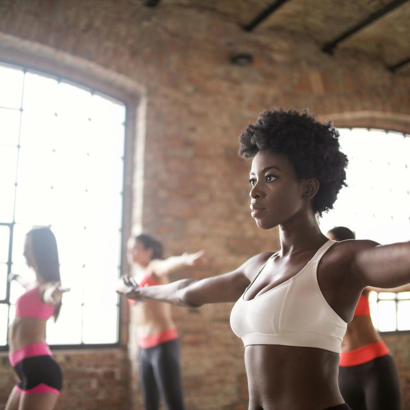 Women in gym doing arm circles or arm exercises stretches