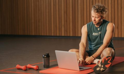 man sitting remote personal training workout at home laptop exercise