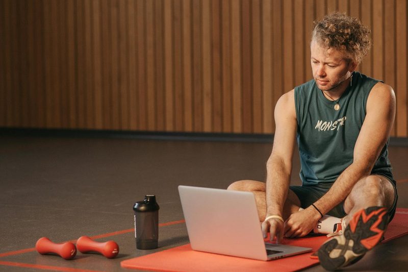 man sitting remote personal training workout at home laptop exercise