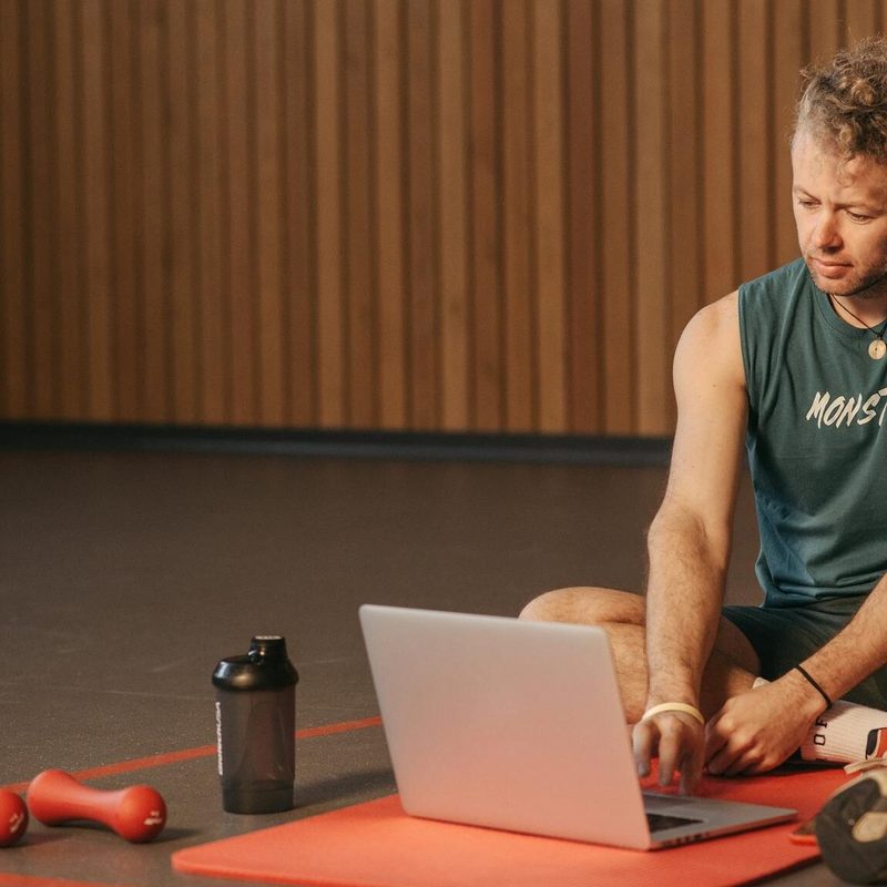 man sitting remote personal training workout at home laptop exercise