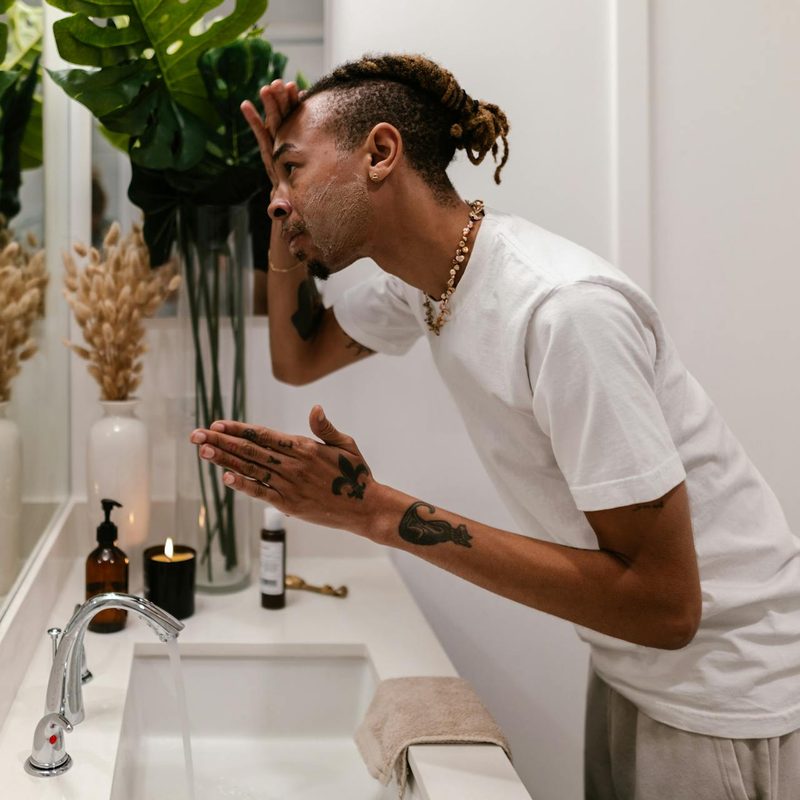 Man looking in the mirror using a skincare product