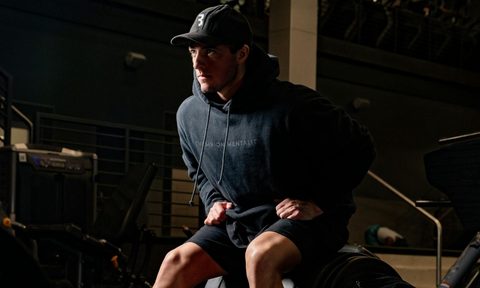 man wearing hoodie sitting on gym machine workout exercise
