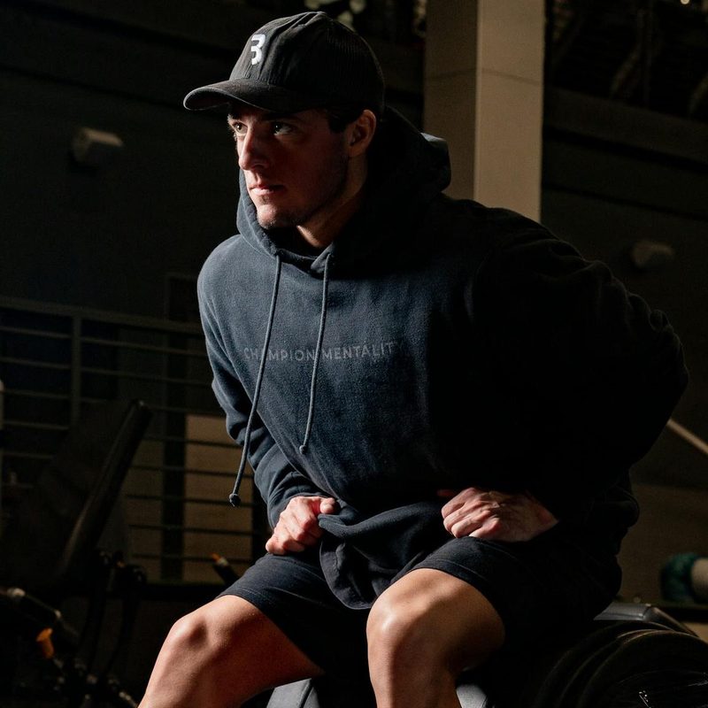 man wearing hoodie sitting on gym machine workout exercise