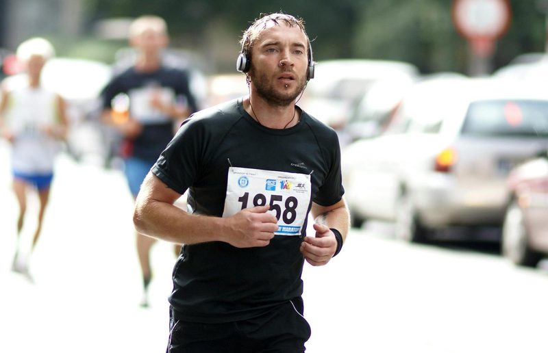 man running marathon headphones black t shirt outside