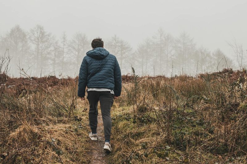 man walking outside with coat in nature