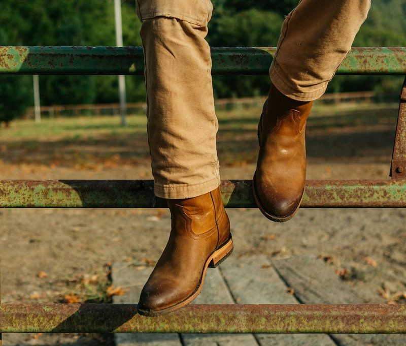 Rhodes boots on model sitting on wood fence