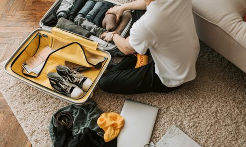 A man packing clothes in his suitcase