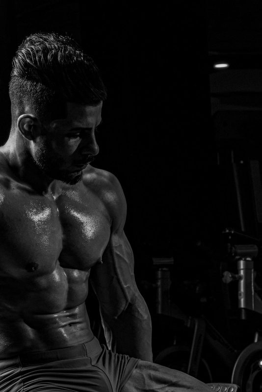 man sitting on bench black and white image abs muscular muscles gym