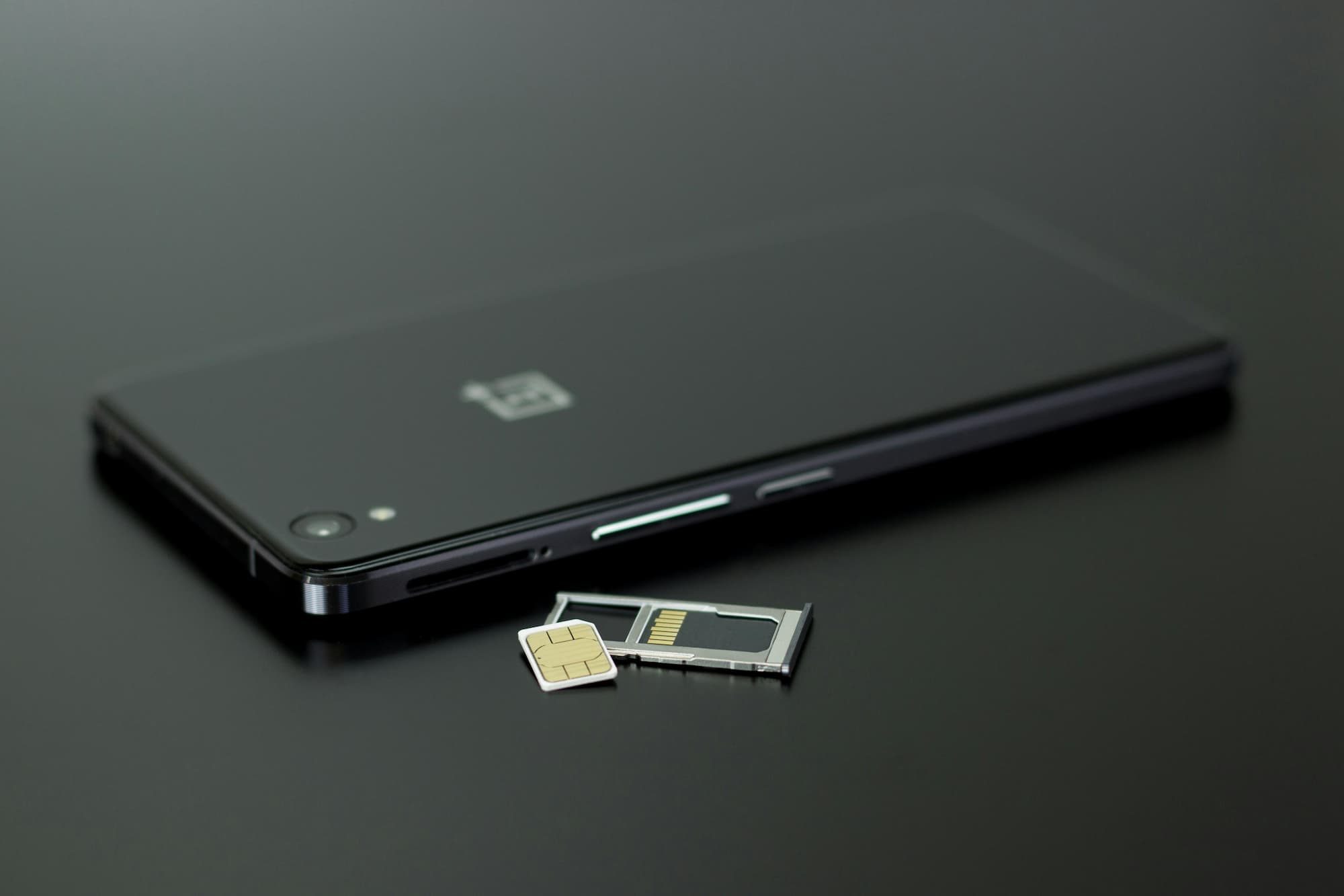 black smartphone on table next to a SIM card