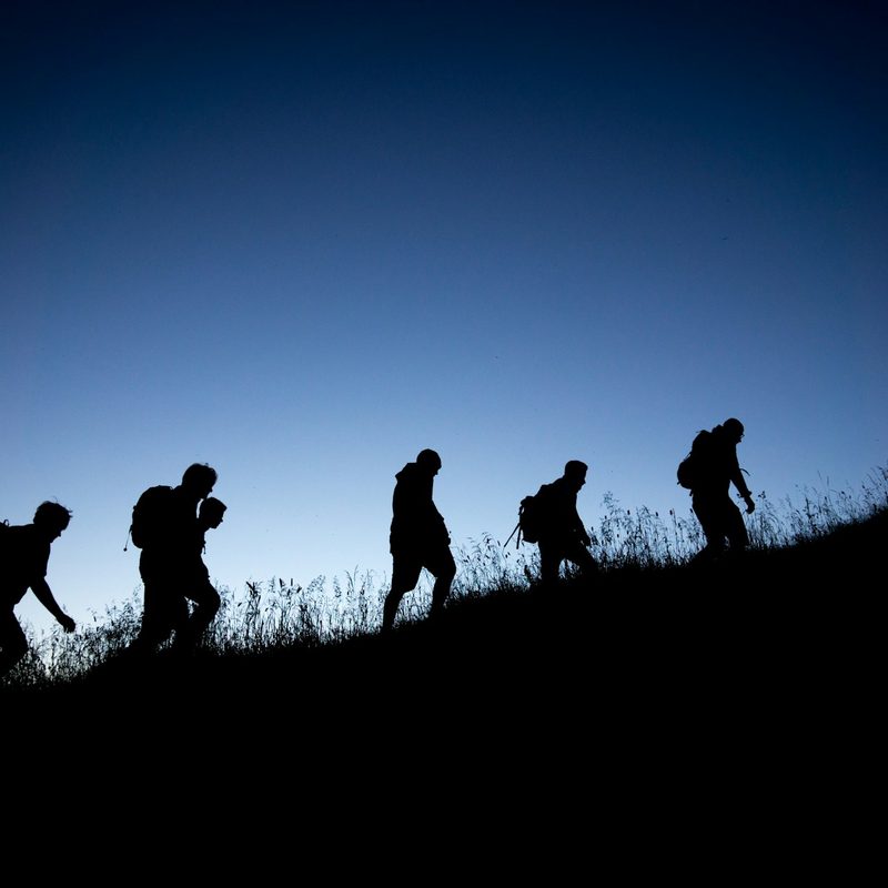 Group of hikers hiking through a meadow at night