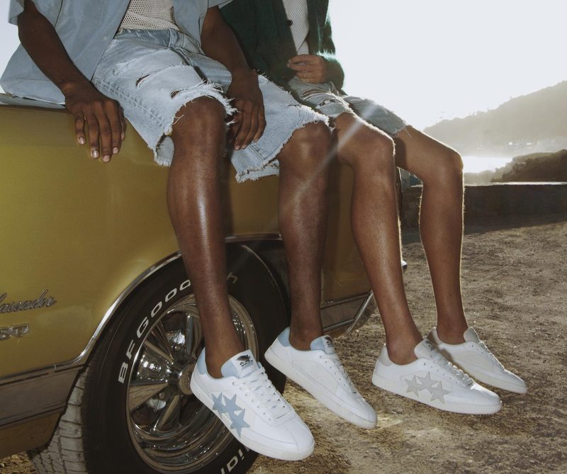 two men wearing white athletic sneakers sitting on car