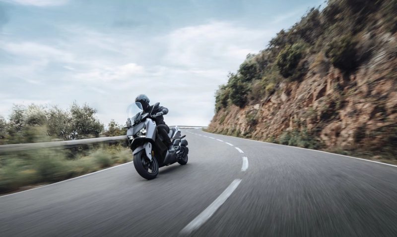 2024 Yamaha XMAX scooter left fron tthree-quarter shot driving up on a decline on a curvy mountain road.