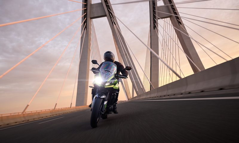 2025 Triumph Tiger Sport 660 direct frontal view as it drives off a modern suspension bridge.
