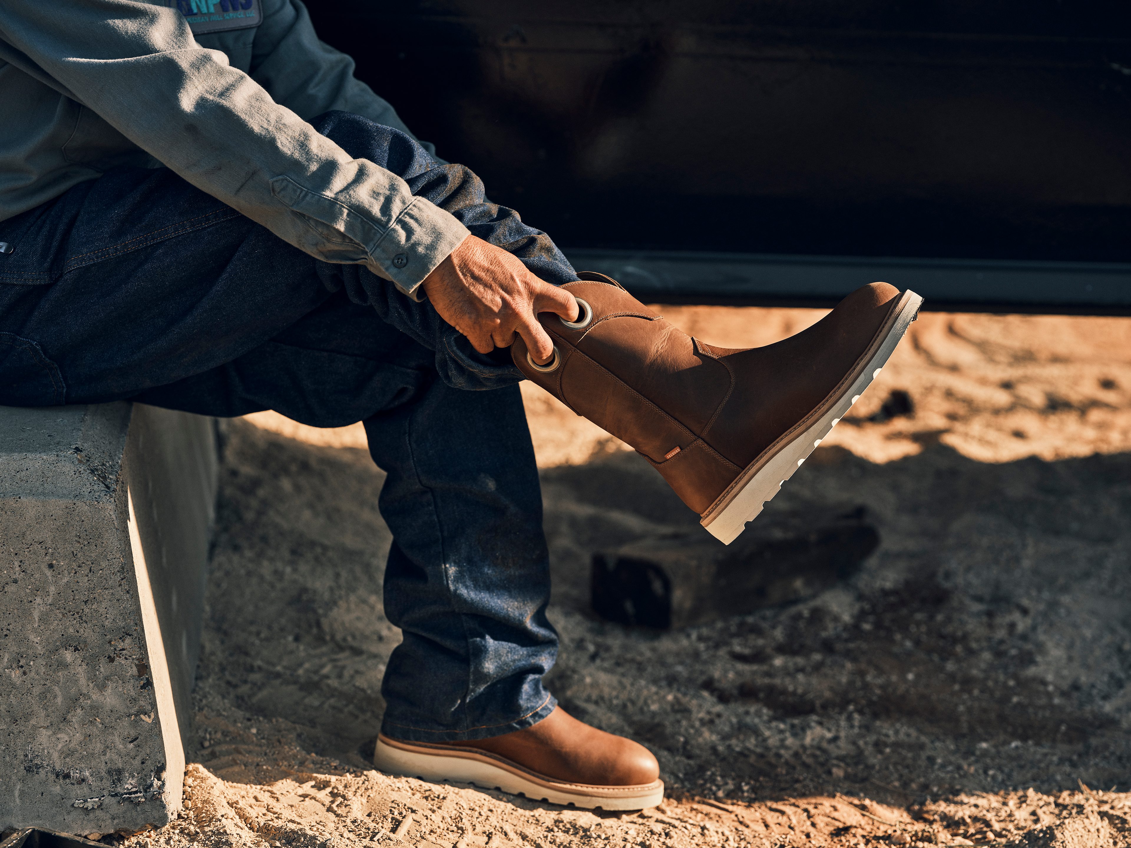 man putting on western work boots